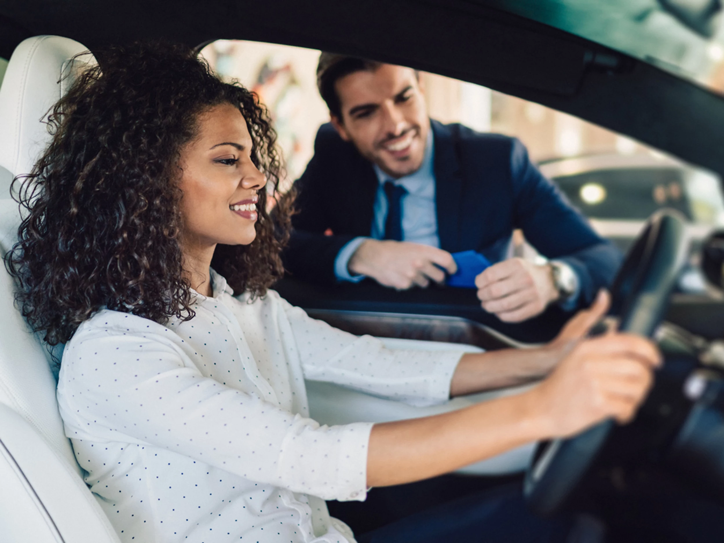 Kundin am Steuer eines Fahrzeugs im Gespräch mit einem Berater